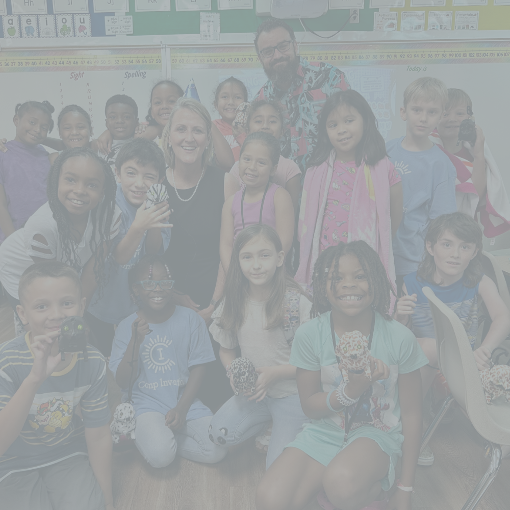Dr. Fey smiling with a group of students in a classroom posing for a photo.