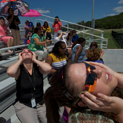 Faculty and guests view the eclipse from the stadium at Roy J Smith middle school. 