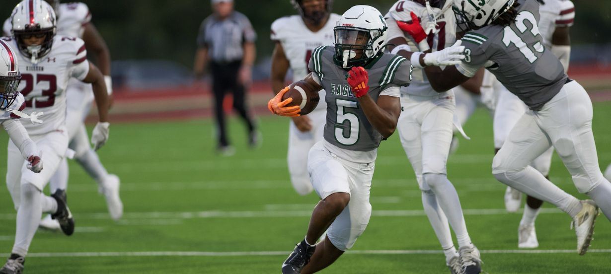 Player runs with th eball on football field