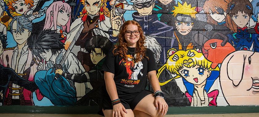  New Ellison graduate poses with her original mural in EHS hallway