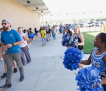 Cheerleaders welcome guests to open house
